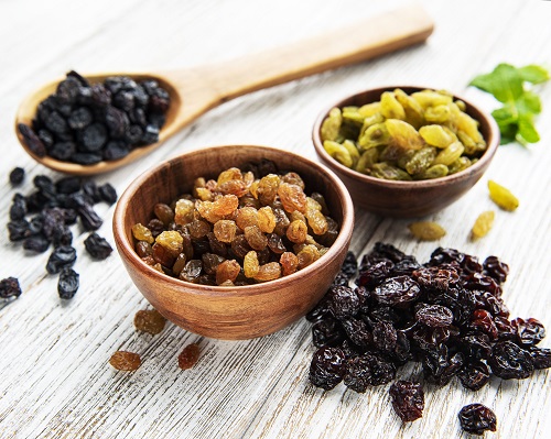 Collection of various raisins on a white wooden background